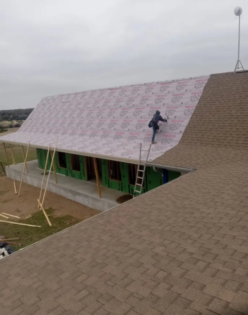 Worker preparing underlayment for a metal roof installation in Richmond Heights